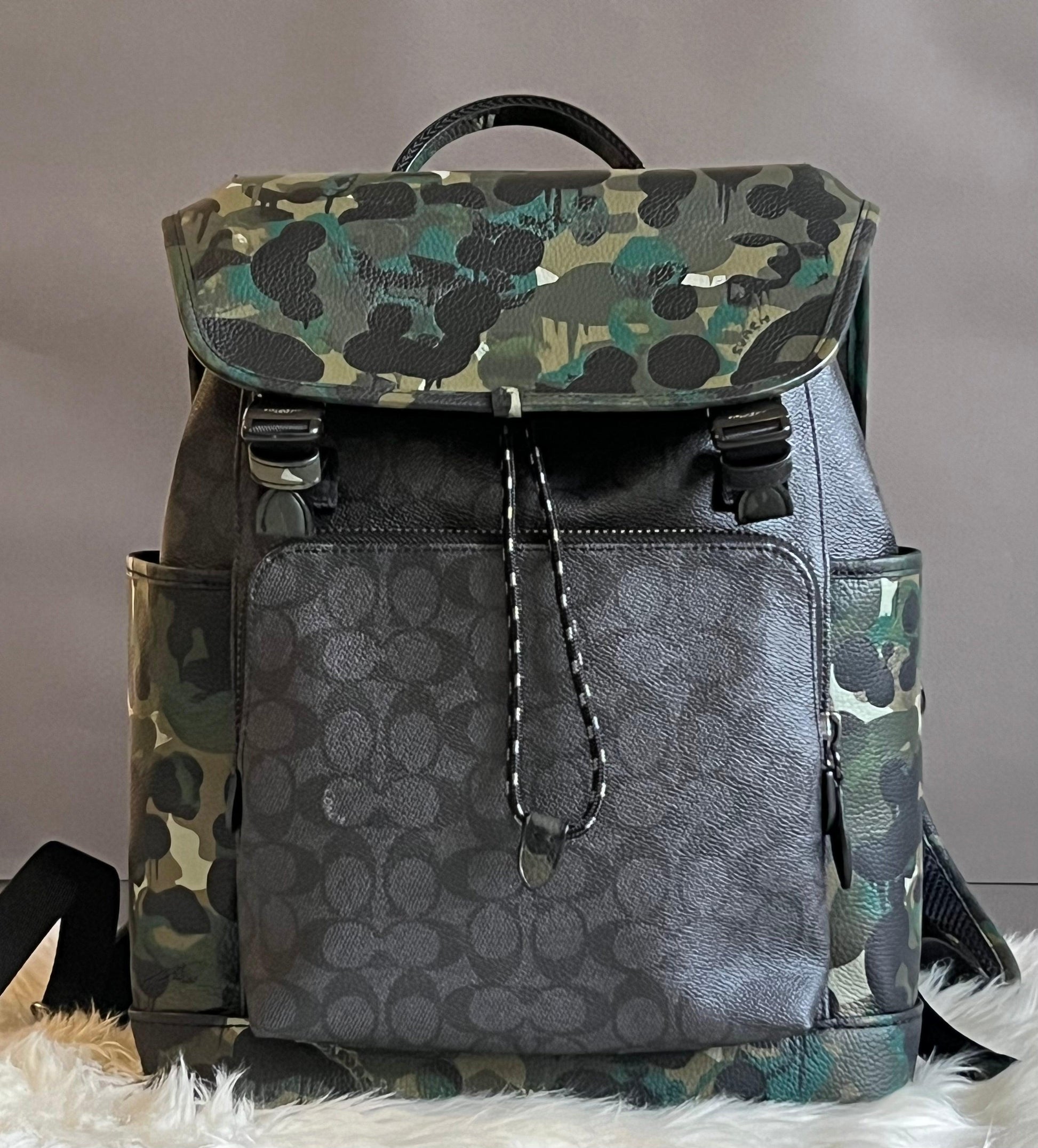 coach camouflage backpack men green multi Outlet West In Signature Camo Print Signature coated canvas and smooth calf leather Inside zip cell phone and multifunction pockets Inside tech sleeve Drawstring and speedclip closures fabric lining Top handle with 2 1/4 drop Outside zip and slip pockets Outside zip access to interior Adjustable shoulder straps 10 1/2 (L) x 16 1/2 (H) x 6 (W) Style No. Coach Outlet Track Backpack In